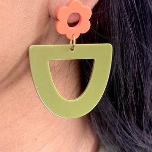 May include: A pair of earrings featuring a green geometric shape and a coral flower charm.