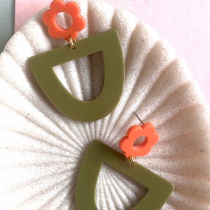 May include: A pair of earrings featuring a green geometric shape and a coral flower charm.