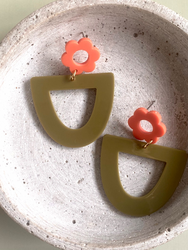 May include: A pair of earrings featuring a green geometric shape and a coral flower charm.