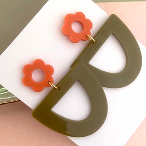 May include: A pair of earrings with a green half-circle shape and a coral flower charm.