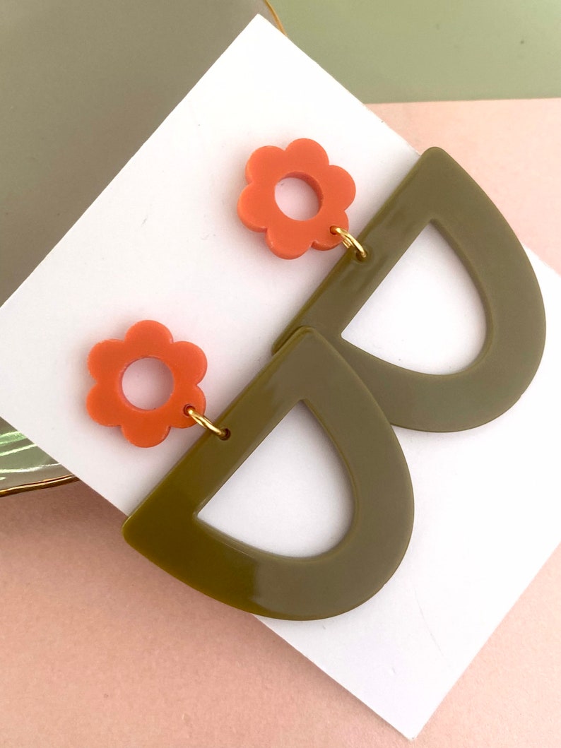 May include: A pair of earrings with a green half-circle shape and a coral flower charm.