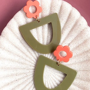 May include: A pair of green and coral earrings with a geometric shape and a flower design.