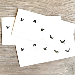 May include: Two sheets of white paper with black silhouette images of birds. The birds are flying in different directions.