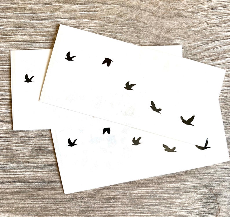 May include: Two sheets of white paper with black silhouette images of birds. The birds are flying in different directions.