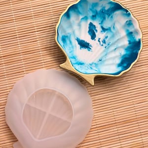 Könnte beinhalten: Eine weiße Silikon-Muschelform mit einem geteilten Innenraum und einem blauen und weißen Muschel-Harzguss.