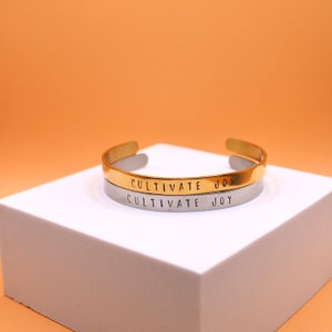 Cultivar la alegría / Pulsera de puño de acero inoxidable ajustable estampada a mano / Oro o plata