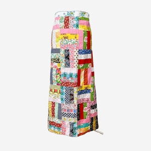 May include: A long patchwork skirt made from colorful fabric scraps. The skirt is made in a block pattern with a variety of floral prints, stripes, and geometric designs.