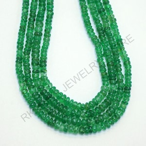 May include: A collection of multiple strands of vibrant green emerald beads. The beads are small, round, and evenly sized, creating a lush, textured appearance. The strands are arranged closely together, showcasing the rich color and natural beauty of the gemstones.