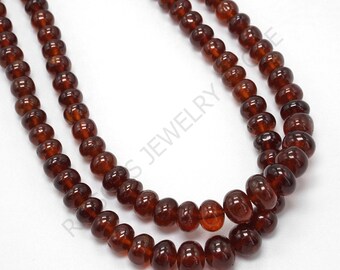 May include: A strand of dark red gemstone beads. The beads are round and have a smooth, polished finish. The strand is made up of two rows of beads.