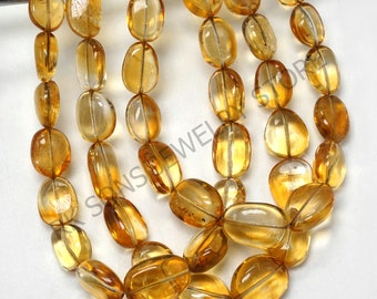 May include: A strand of translucent, oval-shaped, golden yellow citrine beads. The beads are smooth and polished, with a slight variation in size and shape.