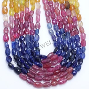 May include: A collection of oval-shaped gemstone beads in a gradient of colours, including yellow, pink, blue, and purple. The beads are faceted and strung together, creating a vibrant display. Suitable for jewellery making.