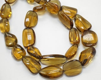 May include: A strand of smooth, translucent, amber-colored gemstone beads. The beads are oval-shaped and have a slightly irregular, natural look.