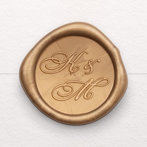 May include: A gold wax seal with the initials "K & M" in a cursive script.