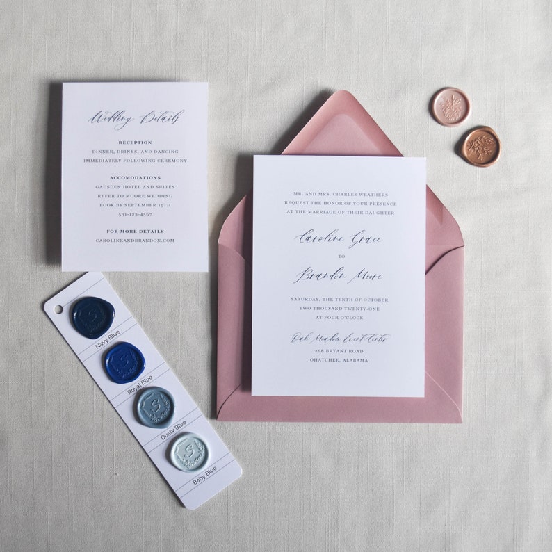 Puede incluir: Conjunto de invitaci&oacute;n de boda con una tarjeta de invitaci&oacute;n blanca dentro de un sobre rosa polvoriento. Incluye tambi&eacute;n una tarjeta de detalles, sellos de cera y una muestra de color de ceras azules. El texto de la invitaci&oacute;n est&aacute; en escritura elegante.
