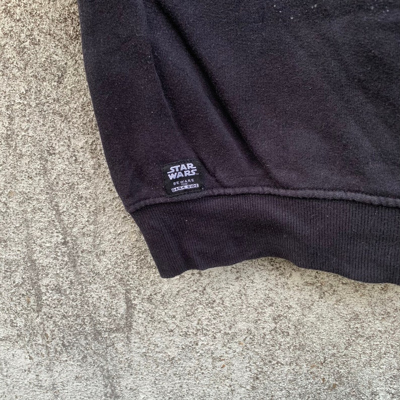 May include: Black sweatshirt with the Star Wars logo and the text "BEWARE DARK SIDE" on a small tag. The sweatshirt is made of a soft material and has a ribbed hem.
