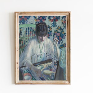 May include: A framed oil painting of a woman in a white dress sitting at a vanity table, surrounded by jewelry and other items. The background is a floral pattern.