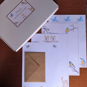 May include: A writing set with a cream box and stationery featuring watercolour illustrations of birds, bees, and flowers. The set includes 40 sheets and 20 envelopes. The stationery has a variety of bird designs, including bluebirds, owls, and robins.