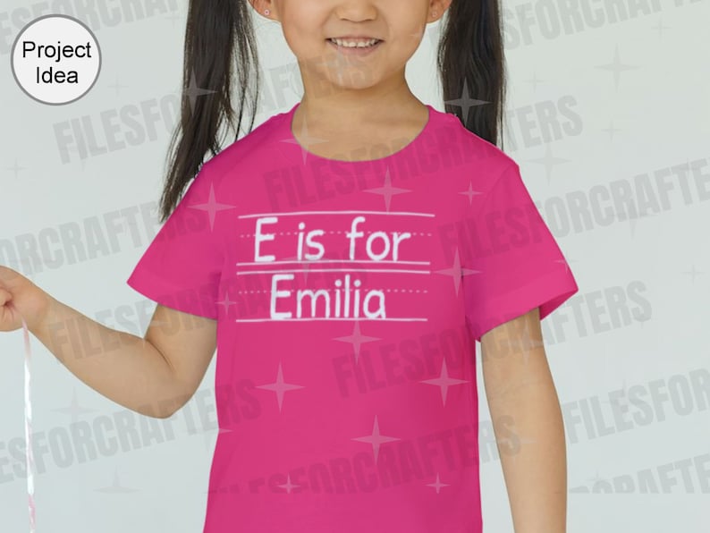 Puede incluir: Camiseta rosa con texto blanco que dice "E es para Emilia".