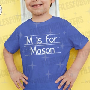 Puede incluir: Una camiseta azul con un dise&ntilde;o blanco que dice "M is for Mason".