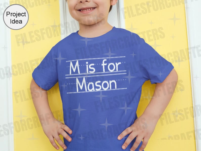 Puede incluir: Una camiseta azul con un dise&ntilde;o blanco que dice "M is for Mason".