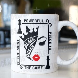 Puede incluir: Taza de cer&aacute;mica blanca con un dise&ntilde;o gr&aacute;fico en blanco y negro que presenta un rostro de mujer con una corona, una pieza de ajedrez y el texto "Powerful, The Most Black Queen, Piece in The Game".