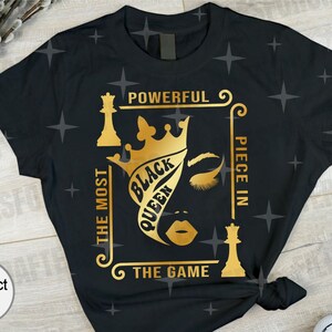 Puede incluir: Camiseta negra con un dise&ntilde;o dorado de una reina de ajedrez con una corona y el texto "The Most Powerful Piece In The Game" y "Black Queen".