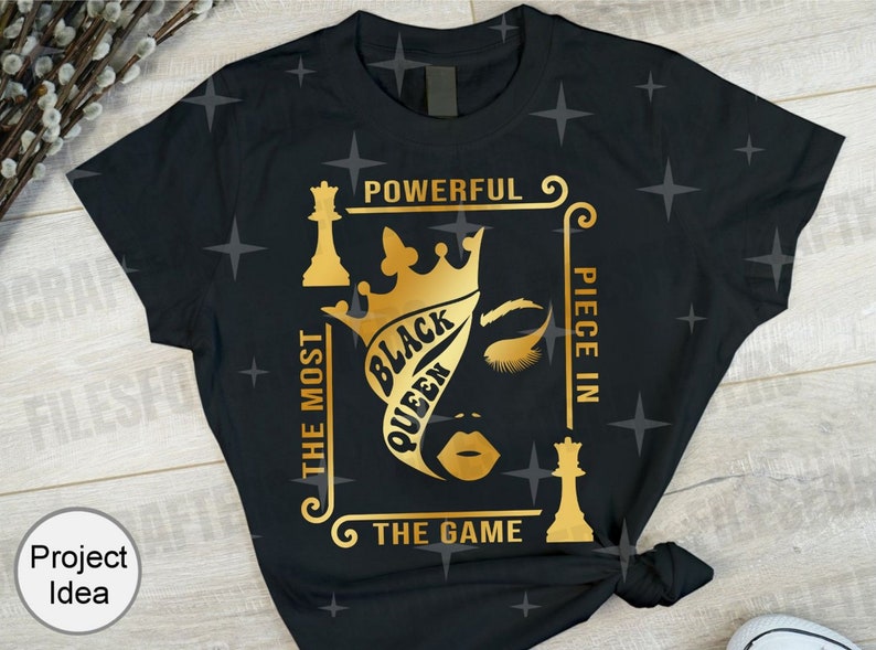 Puede incluir: Camiseta negra con un dise&ntilde;o dorado de una reina de ajedrez con una corona y el texto "The Most Powerful Piece In The Game" y "Black Queen".
