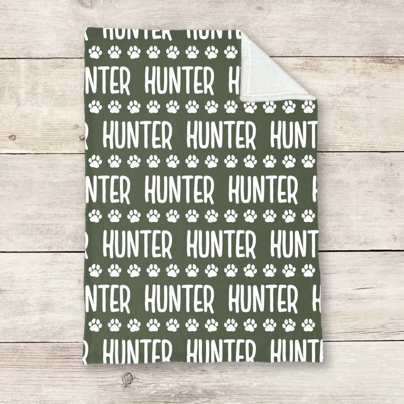 May include: A green fleece blanket with a white paw print and the name "Hunter" repeated in a pattern.