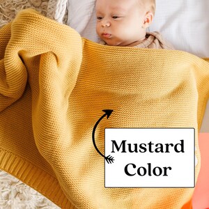 K&ouml;nnte beinhalten: Eine gelbe gestrickte Babydecke in Senffarben. Die Decke ist weich und gem&uuml;tlich, perfekt um ein Baby warm und bequem zu halten.