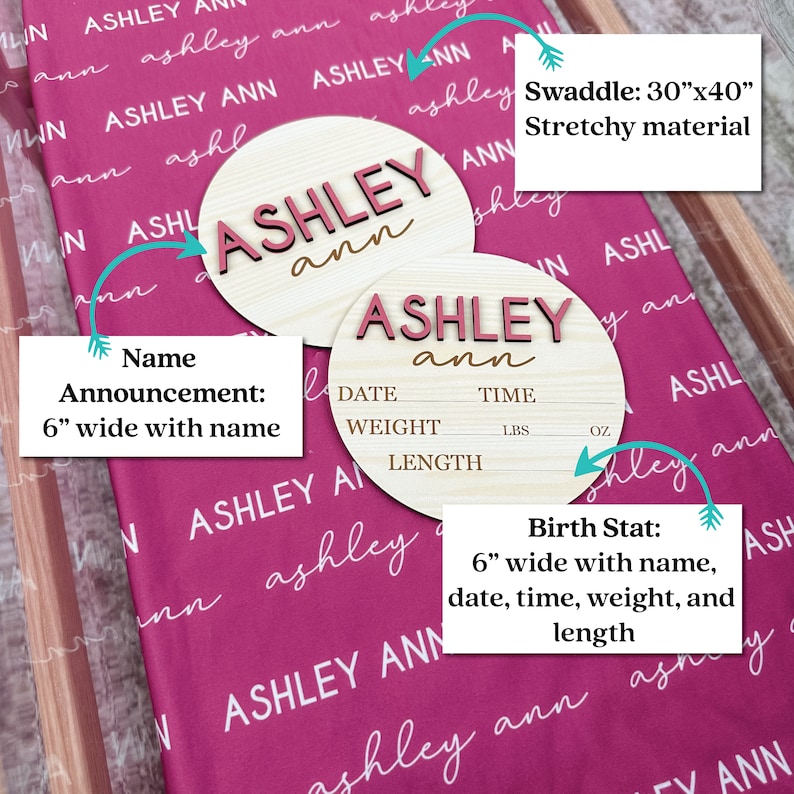 May include: Two wooden round signs with the name "Ashley Ann" written in pink lettering. The larger sign has a space for a date, time, weight, and length. The smaller sign is 6 inches wide. The signs are on a pink fabric with the words "Ashley Ann" repeated in white.