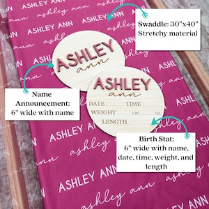 May include: A pink baby swaddle blanket with the name "Ashley ann" printed repeatedly. Two wooden name announcement signs are displayed, one with the name and the other with space for birth stats. The swaddle measures 30" x 40".
