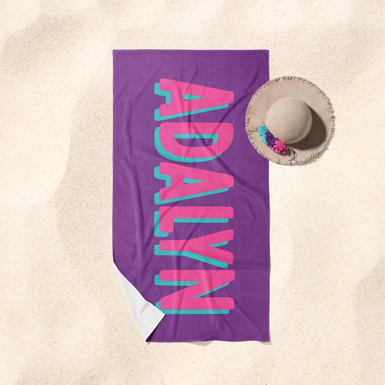 May include: Purple beach towel with the name "ADALYN" in pink and teal letters.