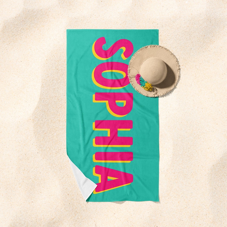 May include: A turquoise beach towel with the name "Sophia" printed in large, pink letters outlined in yellow.