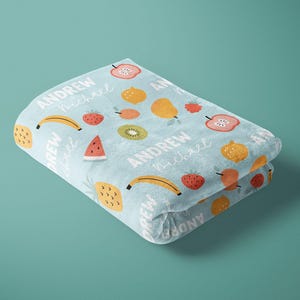 May include: A light blue fleece blanket with a colorful fruit pattern and the names "Andrew" and "Michael" repeated throughout.