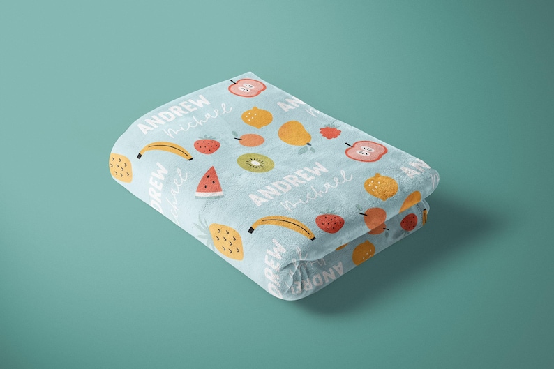 May include: A light blue fleece blanket with a colorful fruit pattern and the names "Andrew" and "Michael" repeated throughout.