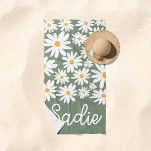 May include: A green beach towel with a white daisy pattern and the name "Sadie" written in white cursive.