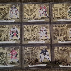 May include: Nine hockey trading cards with sepia-toned images of goalies. Each card displays a goalie's portrait and action shot, with the text "GOALIE ETCHINGS DE GARDIEN" and player names. The cards are in protective sleeves.