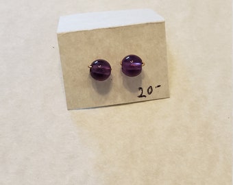 May include: A pair of purple glass earrings with gold wire accents. The earrings are displayed on a white card with the number "20" written on it.