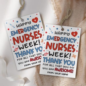 May include: Two white rectangular gift tags with the text "HAPPY EMERGENCY NURSES WEEK! THANK YOU" in red and blue. The tags feature a heart, stars, and medical symbols. Each tag has a string for hanging.
