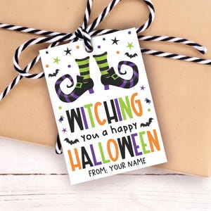 Op de afbeelding: Een rechthoekig wit cadeaulabel met een afbeelding van twee heksenlaarzen met groen en zwart gestreepte kousen. De tekst luidt WITCHING you a happy HALLOWEEN FROM: YOUR NAME, omringd door kleine zwarte vleermuizen, spinnen en kleurrijke sterren.