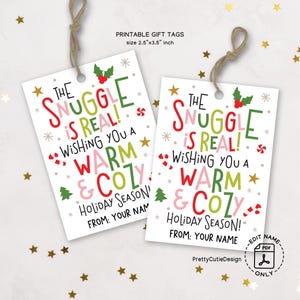May include: Two white gift tags with the text "The Snuggle is Real! Wishing you a Warm & Cozy Holiday Season!" in red, green, and pink. Each tag is 2.5 x 3.5 inches and has a string for hanging. Gold star confetti is scattered around the tags.