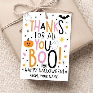 White Halloween gift tag tied with twine to a beige wrapped present, with pink, orange, and black “Thanks for All You Boo! Happy Halloween!” lettering and small spooky icons.