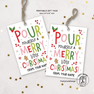Puede incluir: Dos etiquetas de regalo navideñas blancas con el texto "Pour Yourself a Merry Little Christmas!" en rojo, verde y rosa. Cada etiqueta mide 6,35 cm x 8,89 cm y tiene una cuerda para colgar. Las etiquetas están decoradas con bastones de caramelo, estrellas y un hombre de jengibre.