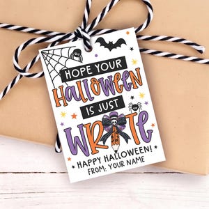 May include: A rectangular white gift tag featuring a spider web, a spider, a bat, and colorful stars. The text reads: HOPE YOUR HALLOWEEN IS JUST WRITE, HAPPY HALLOWEEN!, FROM: YOUR NAME. A pencil with a bow is illustrated in the center.