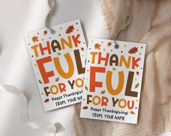 Può includere: Due etichette regalo rettangolari bianche con le parole "THANKFUL FOR YOU" in arancione, marrone e giallo. Le etichette hanno illustrazioni di foglie d'autunno e ghiande e il testo "Happy Thanksgiving! FROM: YOUR NAME".