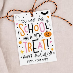 May include: A rectangular white gift tag with black, orange, and pink text reading "YOU MAKE OUR SCHOOL A REAL TREAT! HAPPY HALLOWEEN! FROM: YOUR NAME". The tag features illustrations of a ghost, bat, spider, pumpkin, and candy corn, tied with orange and black twine.