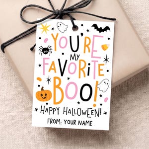 May include: A rectangular white gift tag with black string featuring the text YOU'RE MY FAVORITE BOO! in orange, pink, and black letters. The design includes illustrations of a pumpkin, spider, ghost, bat, and candy corn with HAPPY HALLOWEEN! and FROM: YOUR NAME.