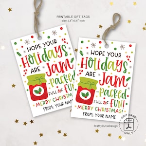May include: Two white rectangular gift tags with the text "HOPE YOUR Holidays ARE Jam-packed FULL OF FUN!" in red, green, and black. Each tag features a jar of jam illustration and a string for hanging. The tags are 2.5 x 3.5 inches.