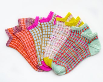 Peut inclure: Cinq paires de chaussettes basses colorées avec des motifs géométriques. Les chaussettes sont dans des tons d'orange, rose, jaune, bleu et vert.