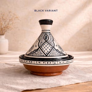 Op de afbeelding: Een keramische tajine-pot met een conische deksel, met een zwart-wit geometrisch ontwerp. De basis is roodbruin en de rand is zwart. De tekst "BLACK VARIANT" staat bovenaan.